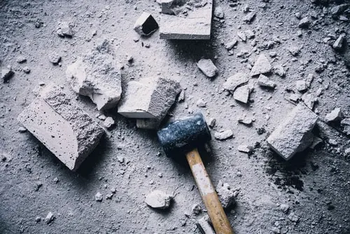 Innenabriss Ein Hammer und Teile einer Wand auf einem staubigen Boden.